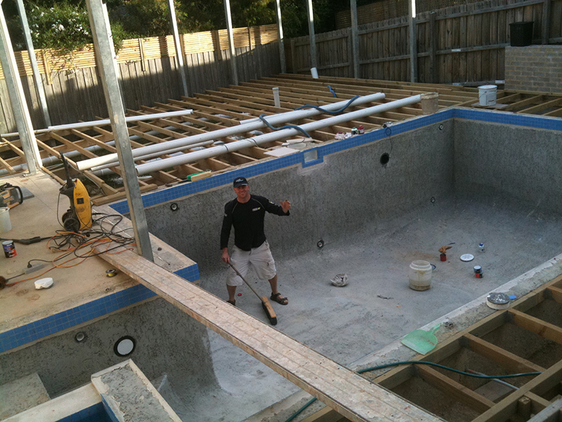 Team member inside a swimming pool shell and construction site. Work in progress image.