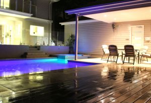 Wooden deck and lit swimming pool.