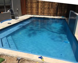 Square swimming pool with feature wall.